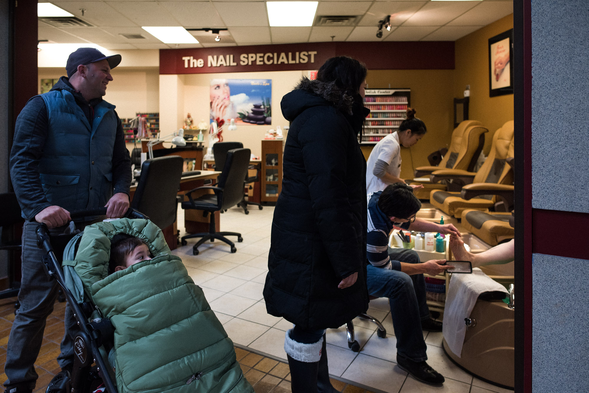 family with stroller talks to lady getting a pedicure at beauty salon