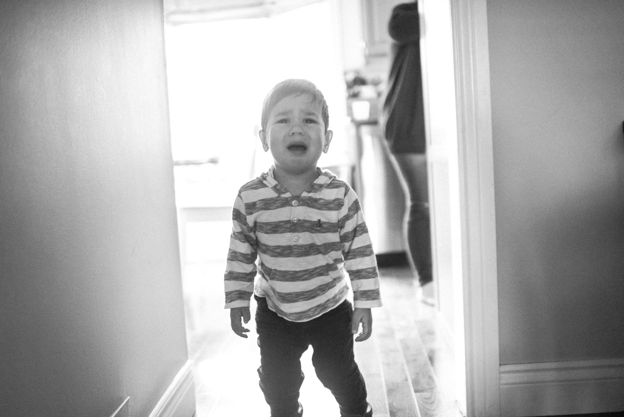 black and white photo backlit boy cries in the hallway 