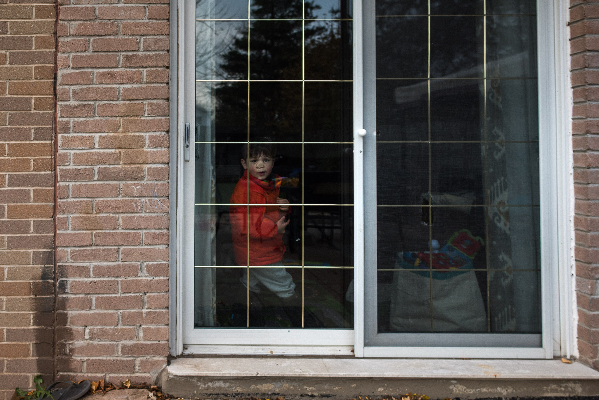 boy scrunches nose against patio door looking out