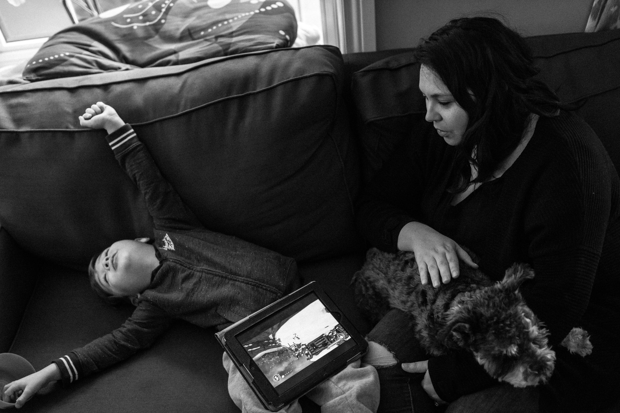 mom looks on as boy stretches on the couch