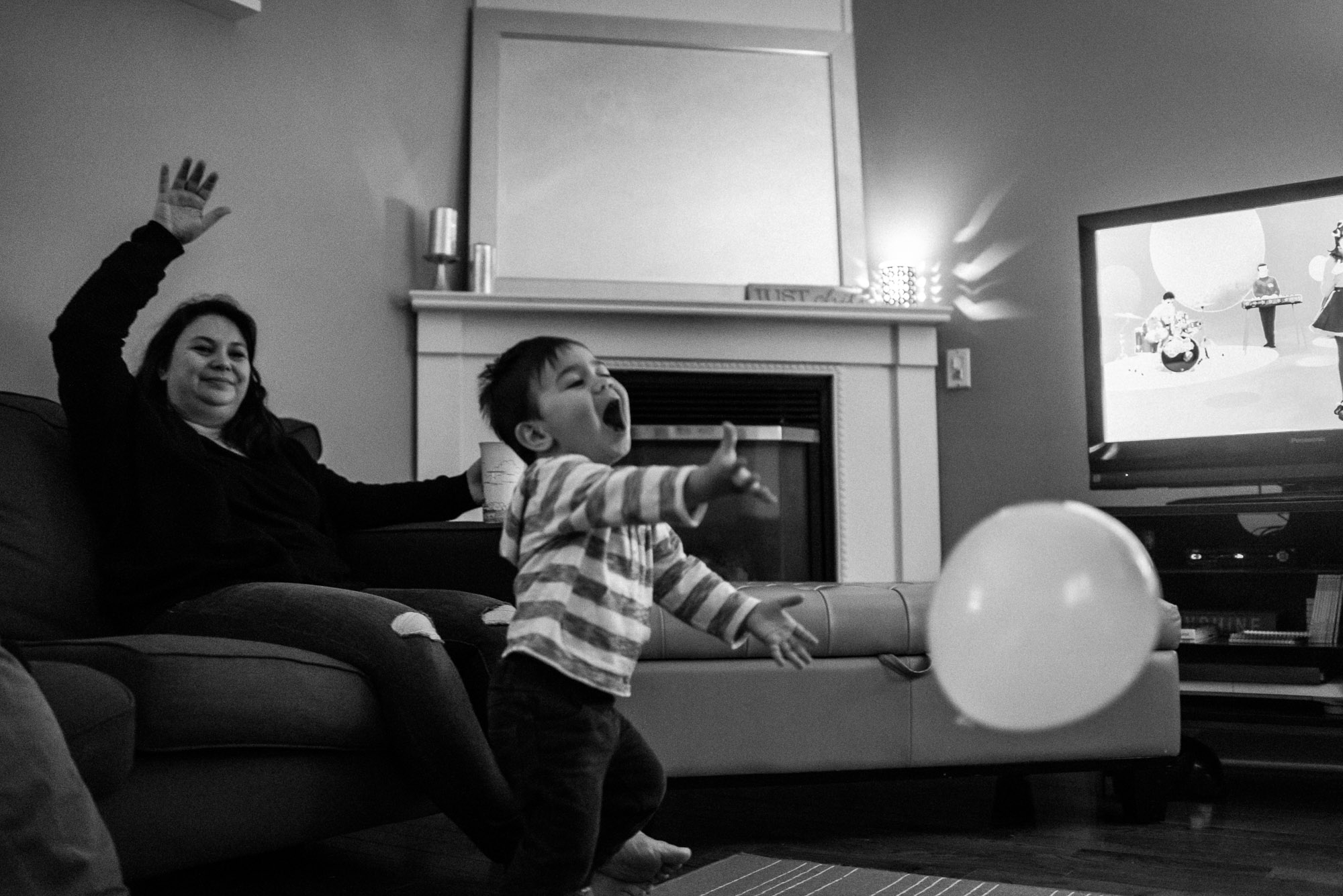 toddler in stripy shirt plays with balloon while mom looks on