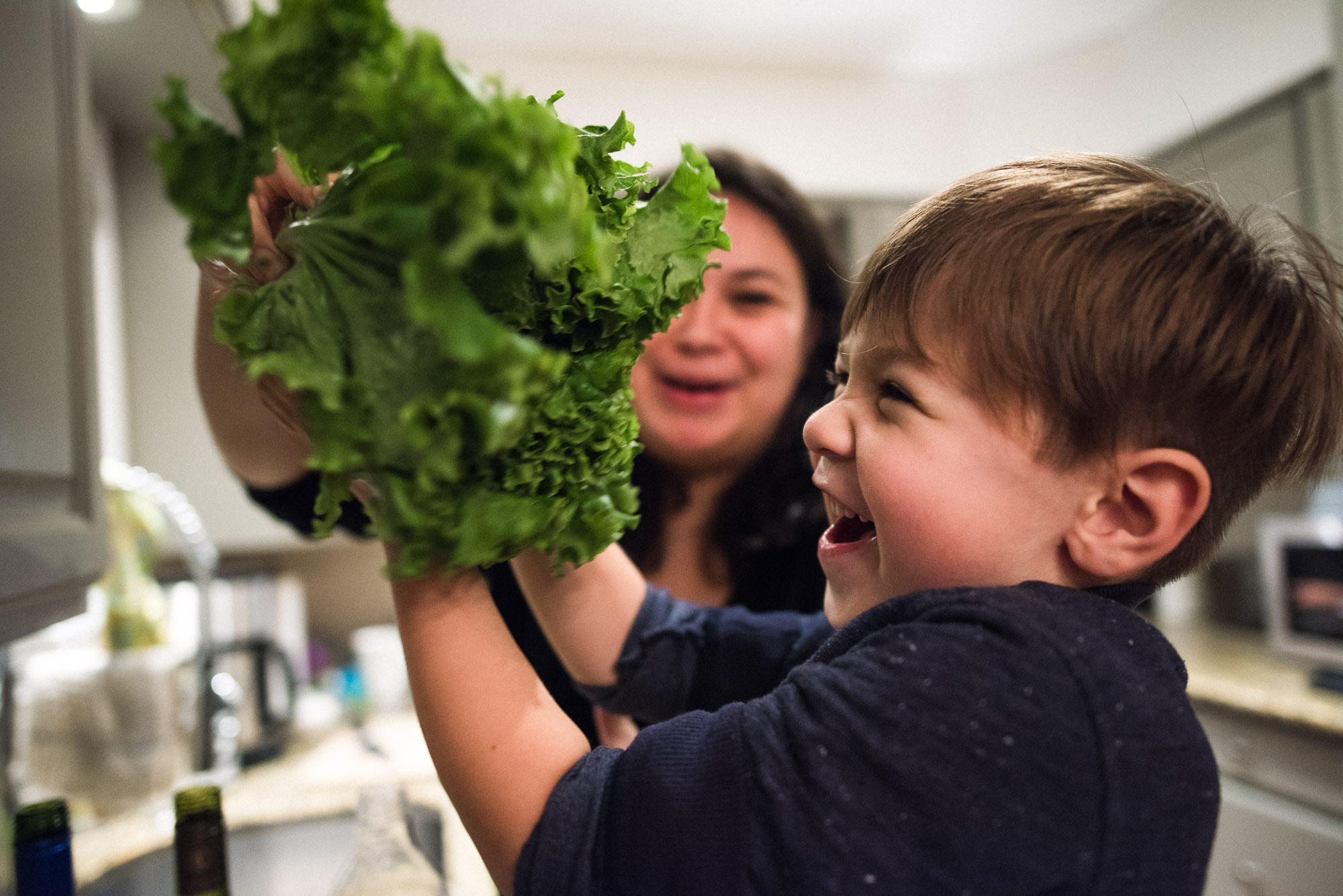 boy and mum laugh over green lettuce
