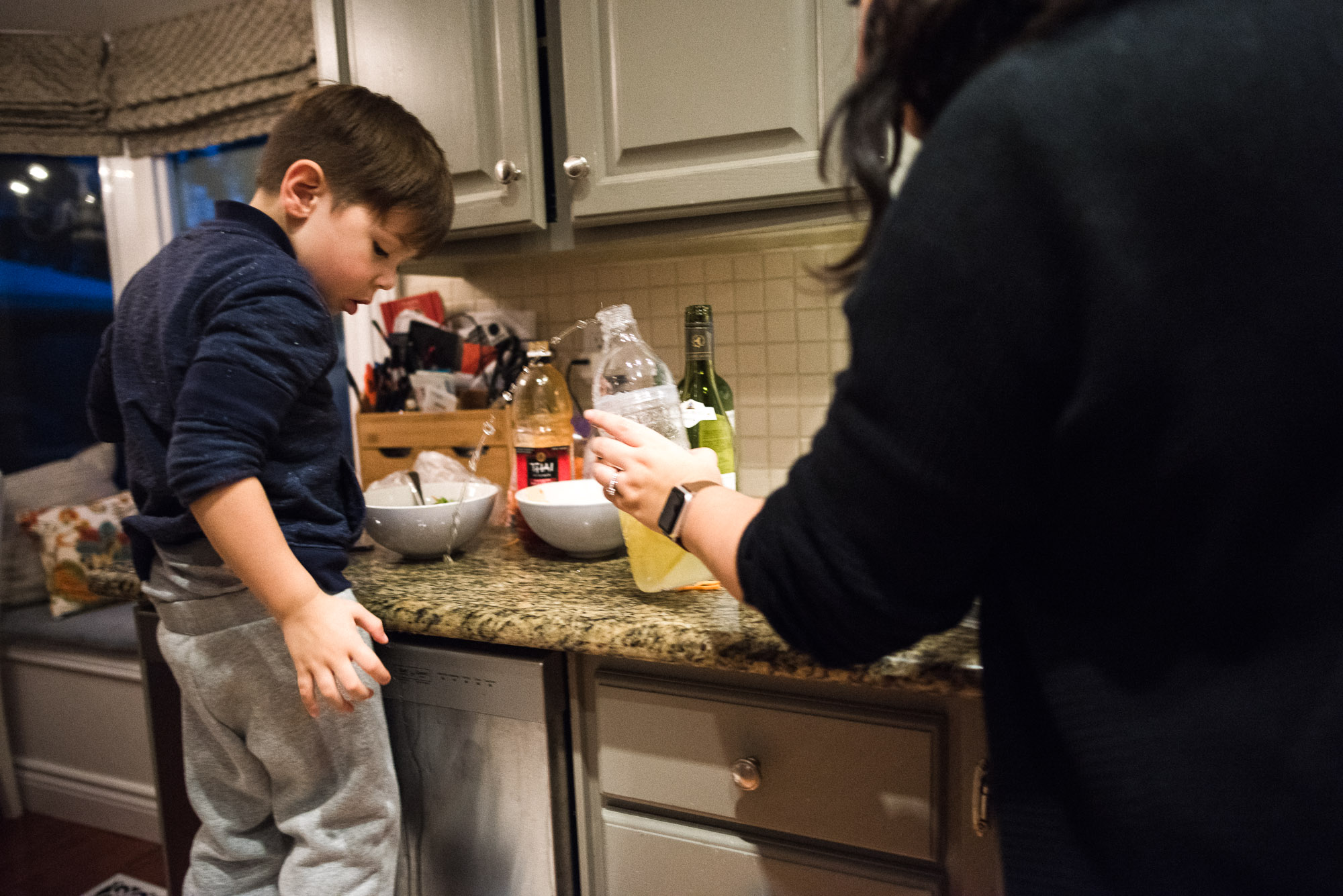 boy looks as mom catches spilling bottle in kitchen