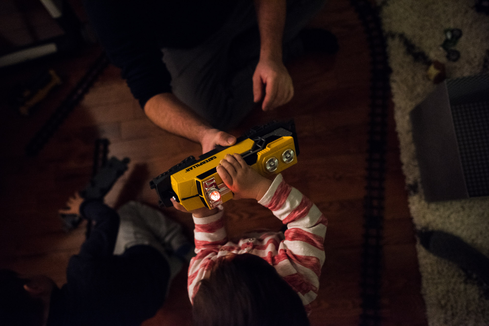 toddler and dad hold up a yellow toy train 