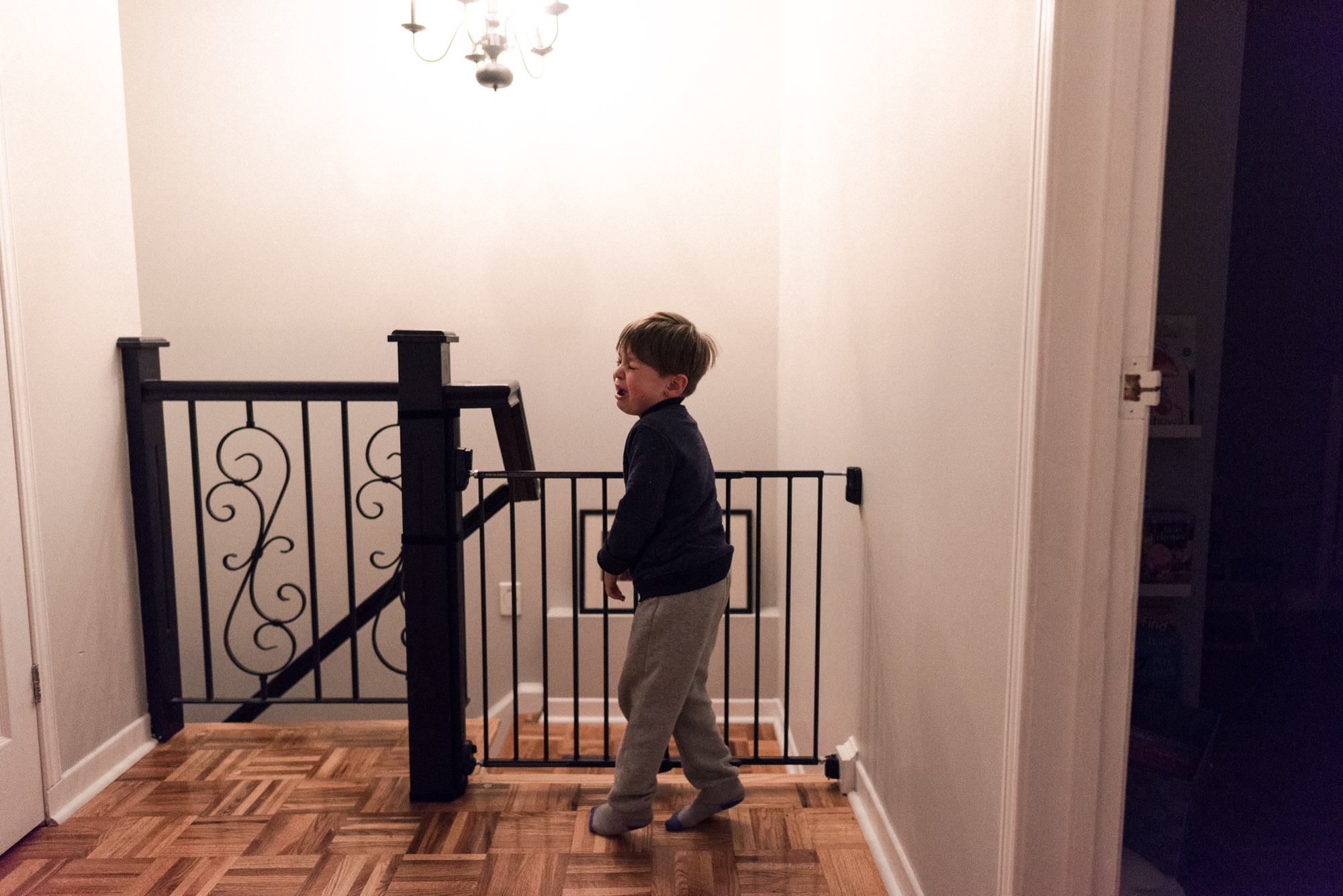boy twirls, crying, at the top of the stairs 
