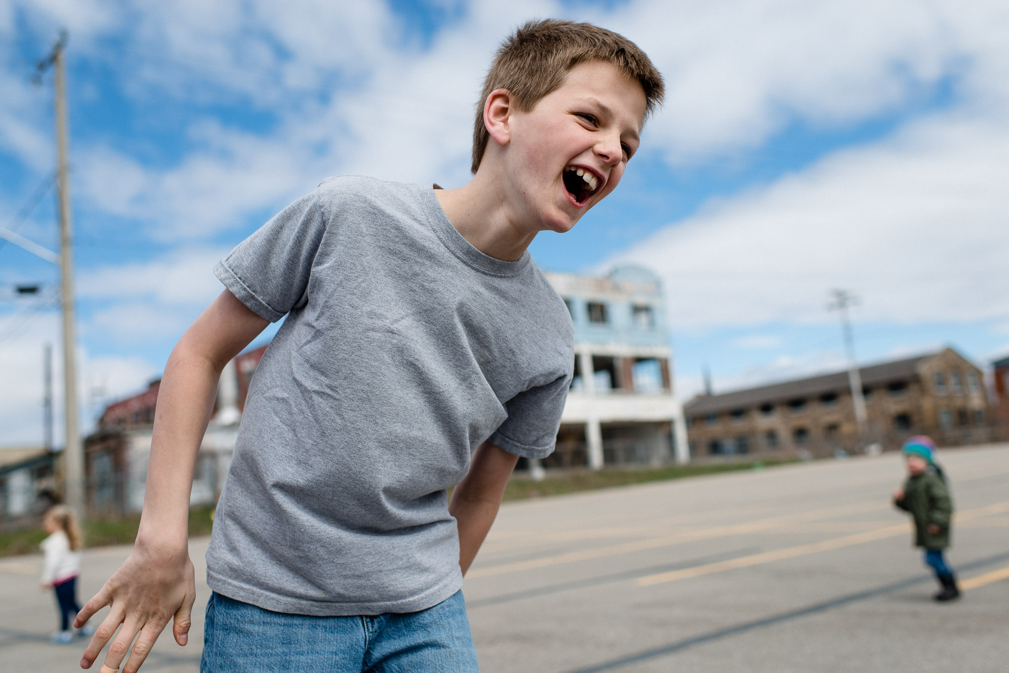 boy laughs against a blue sky with clouds