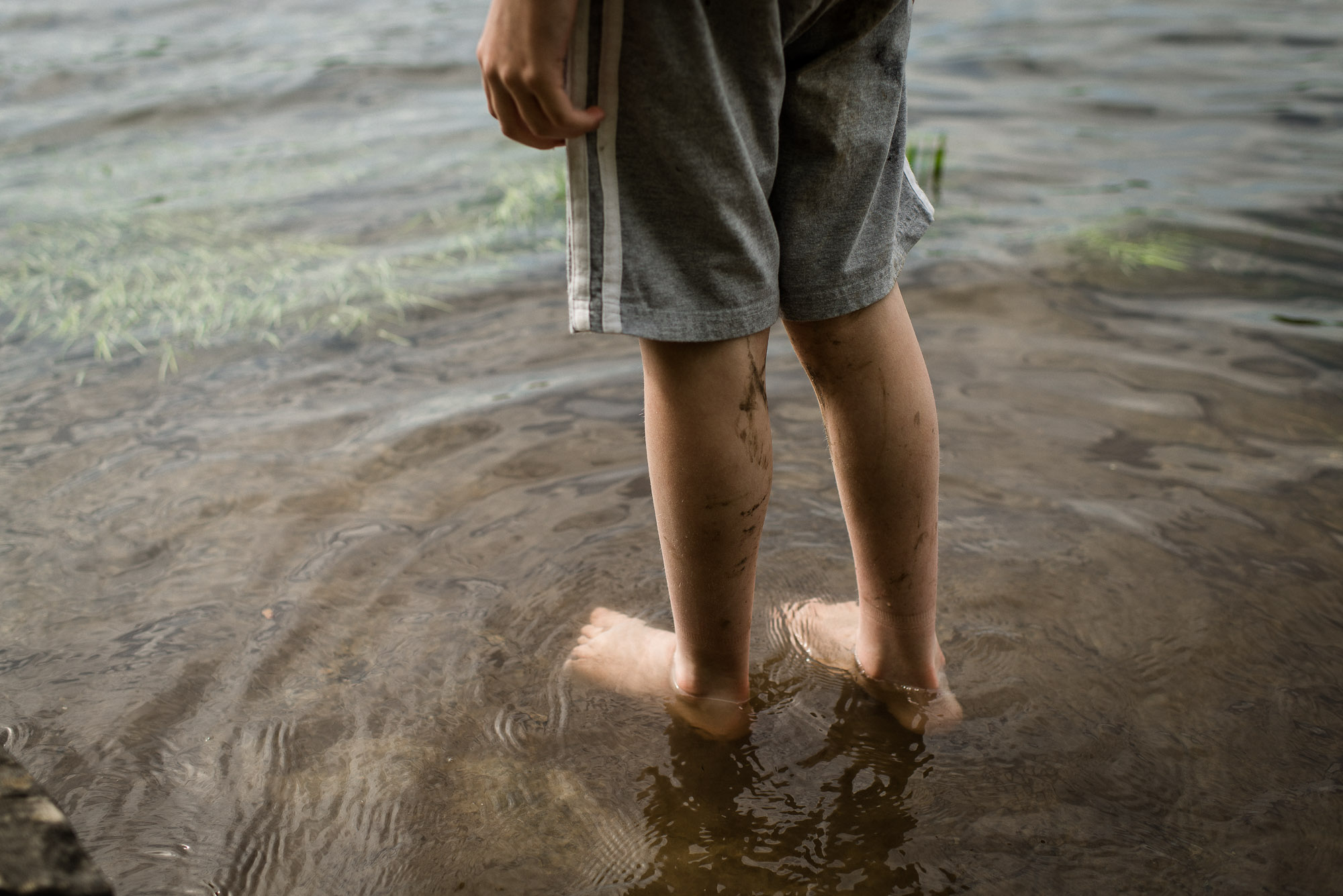 boy's legs wading into lake waters