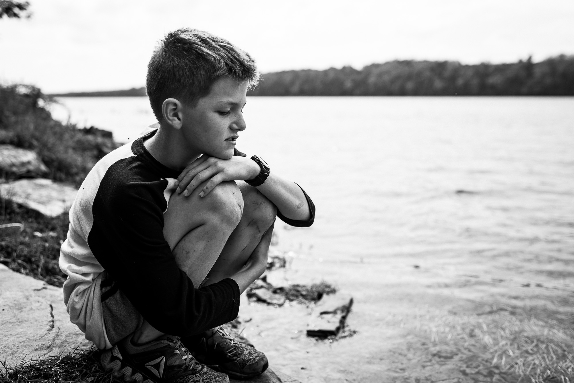 boys sits on shore of lake