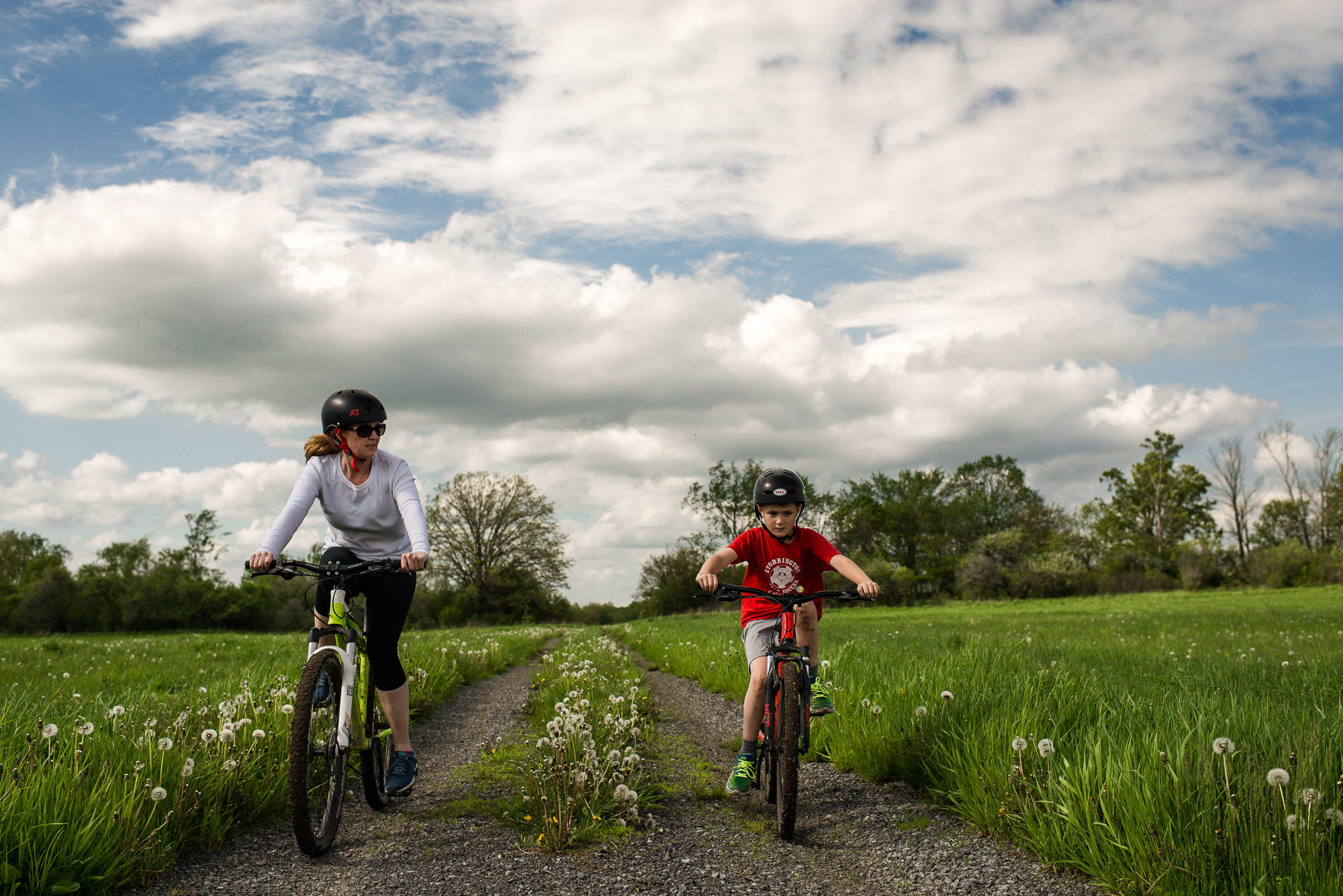 mother and son ride bikes through green field