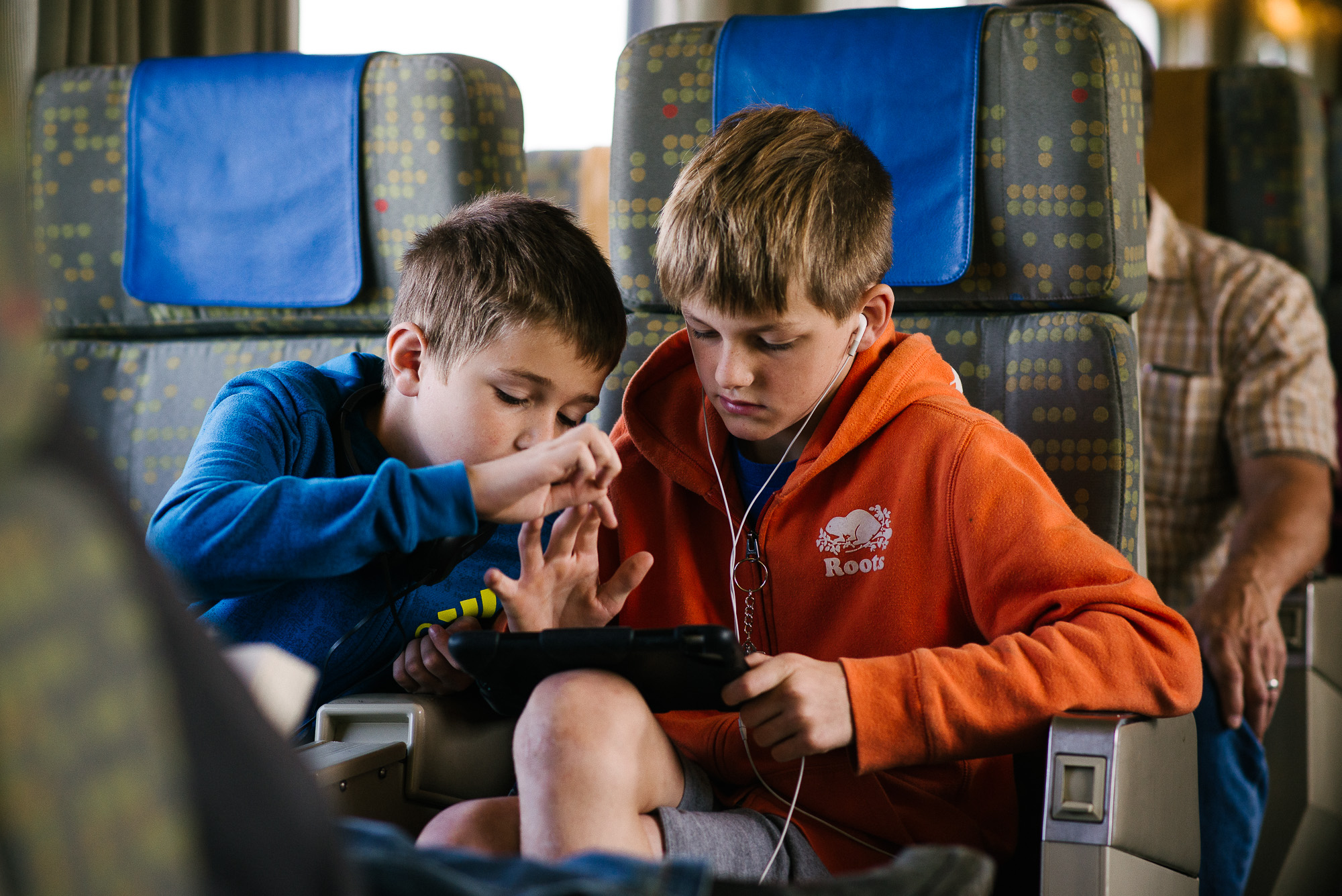 boys look at a game pad on a train