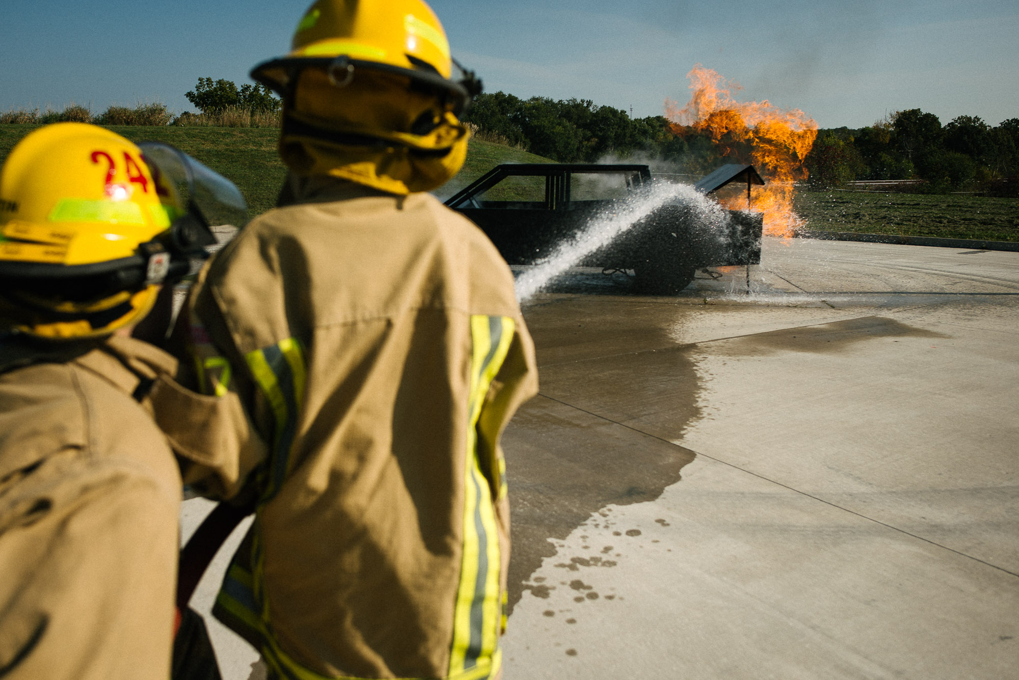 boys in fireman gear put out a mock fire on a training car
