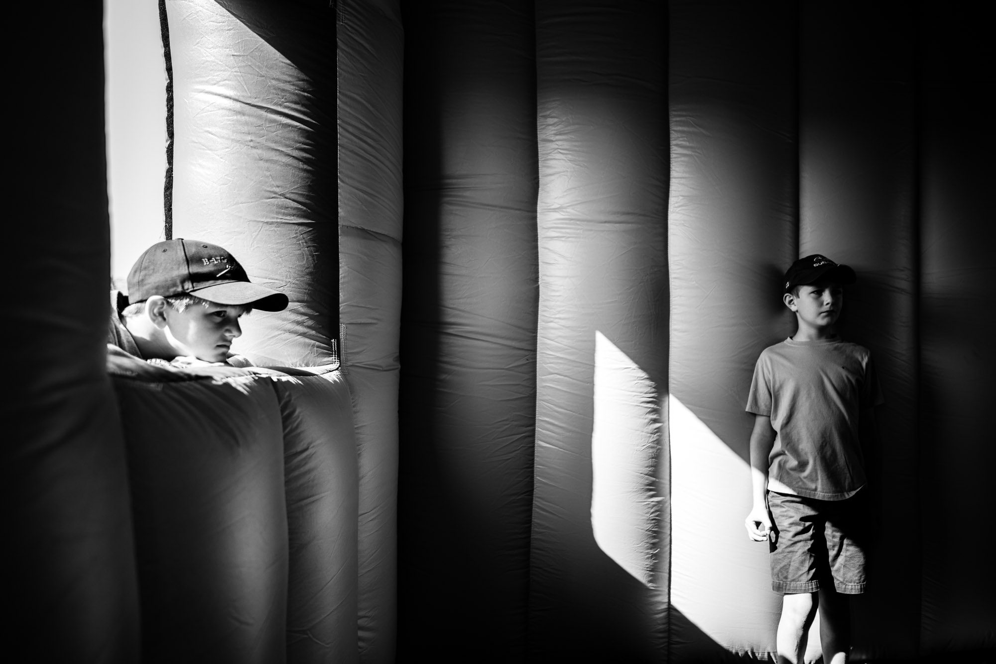 two boys stand around in shadows of a blow-up house