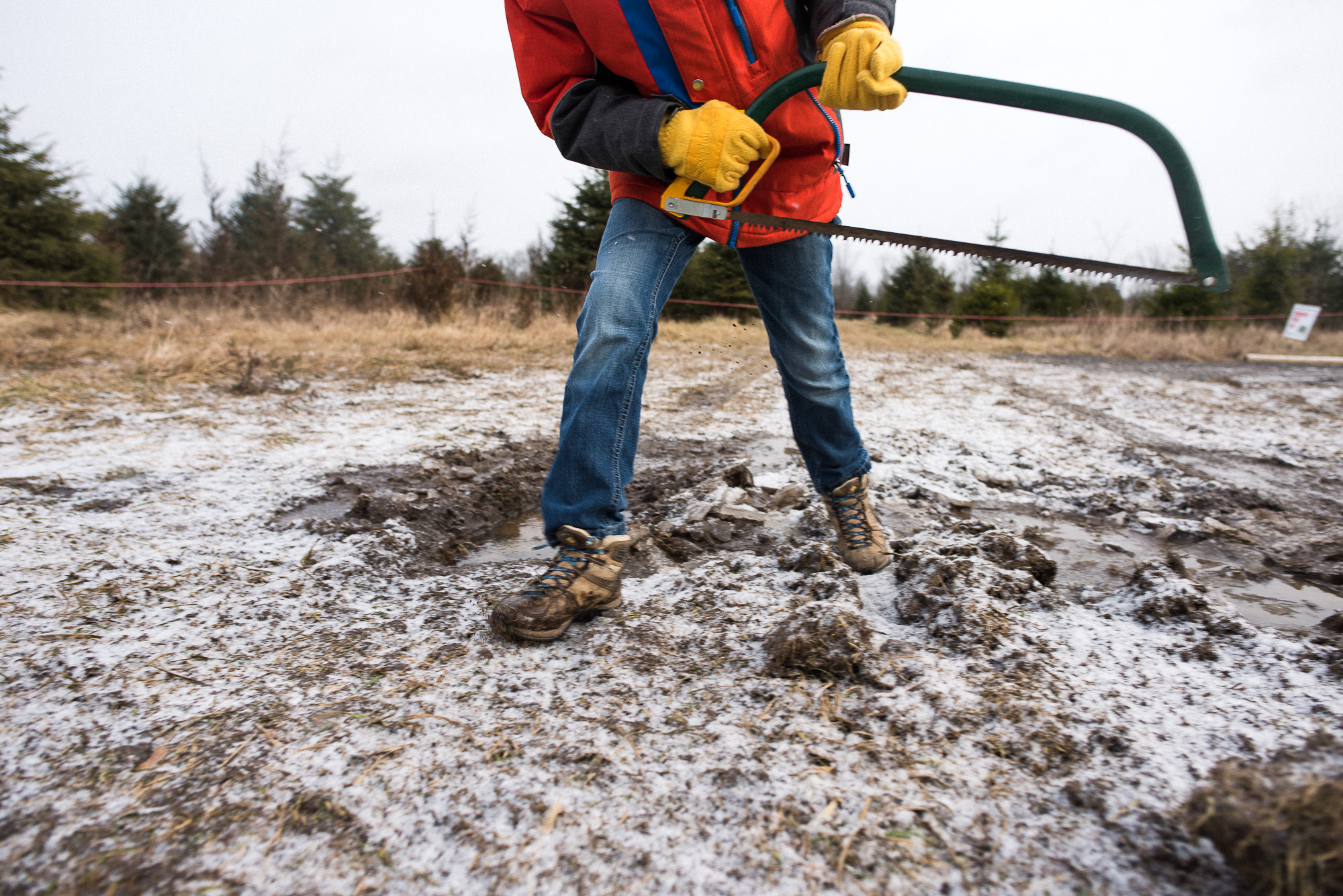 boy in orange jacket holds a saw