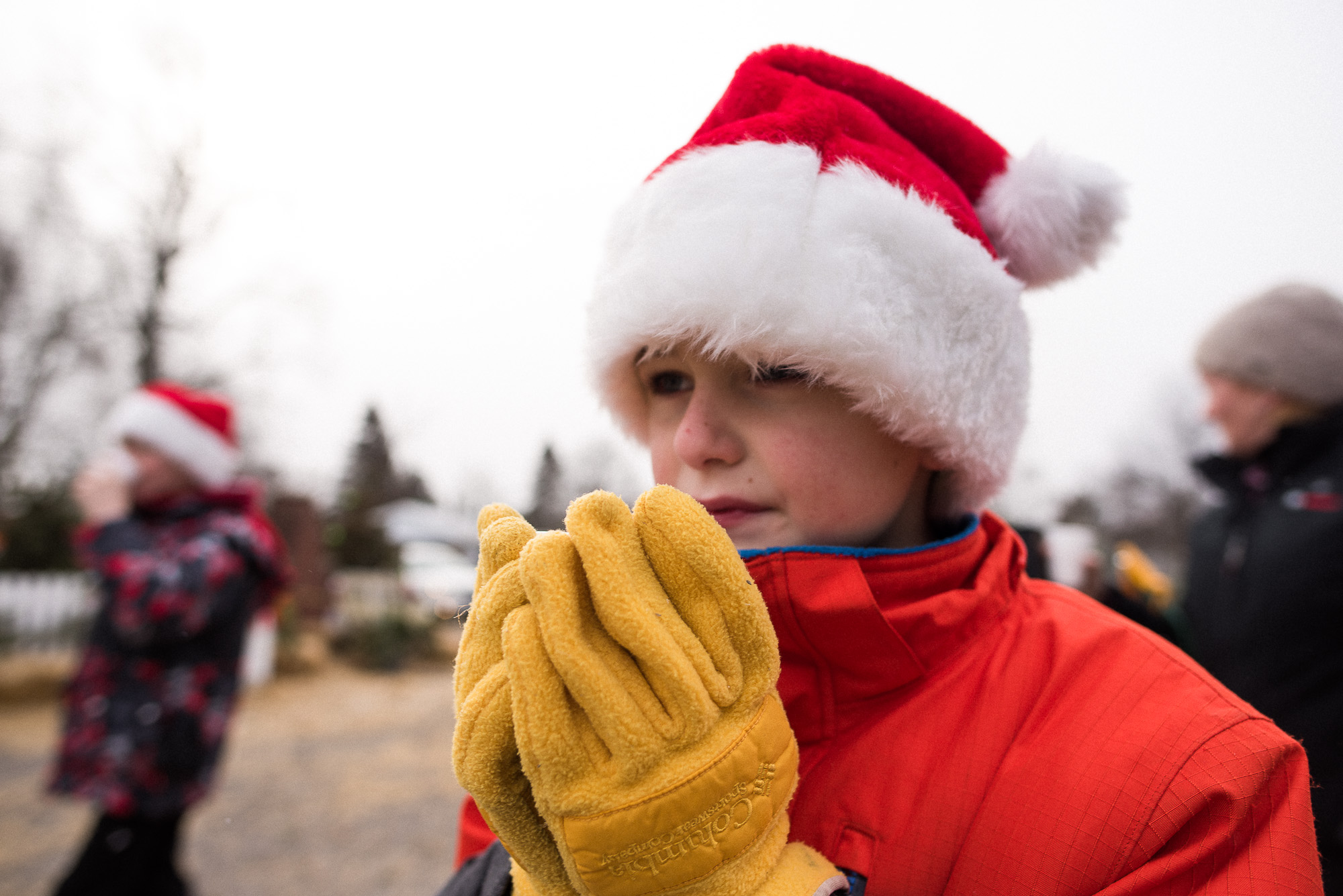 boy with Santa hat holds hot chocolate cut with yellow gloves