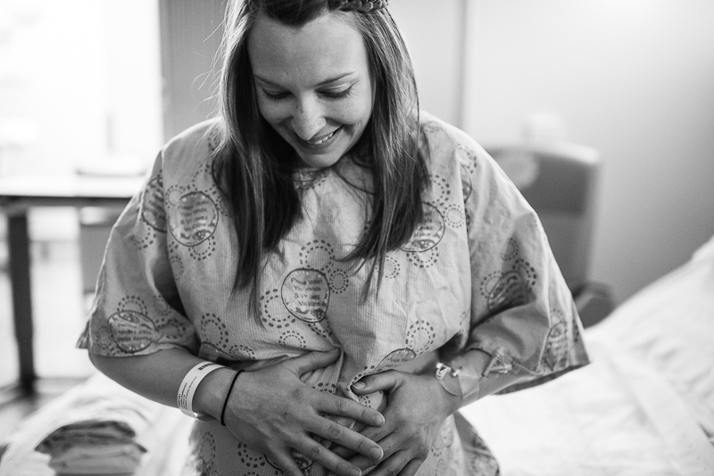 labouring mother holds her belly and smiles