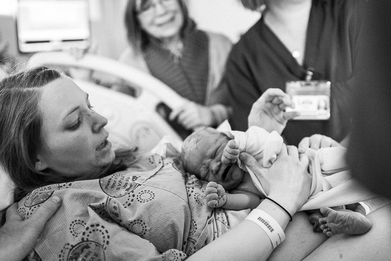 shortly after giving birth mother holds her baby on her stomach