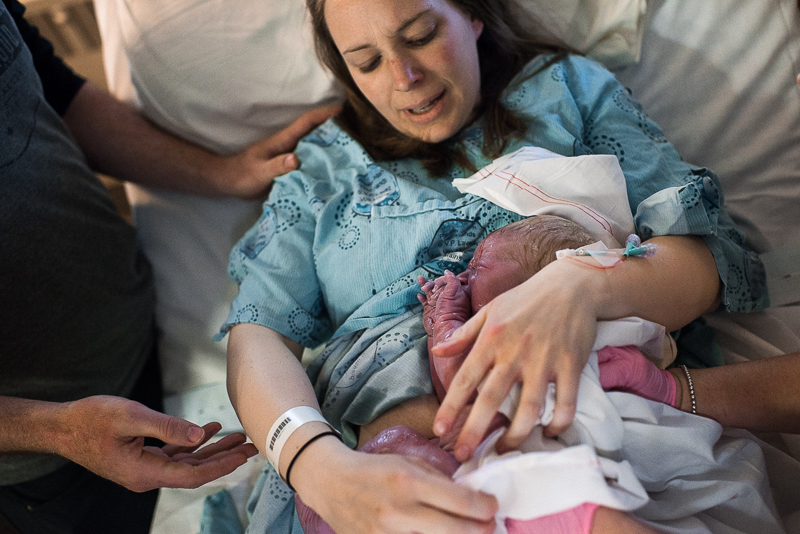 mother holds new infant in her arms after giving birth