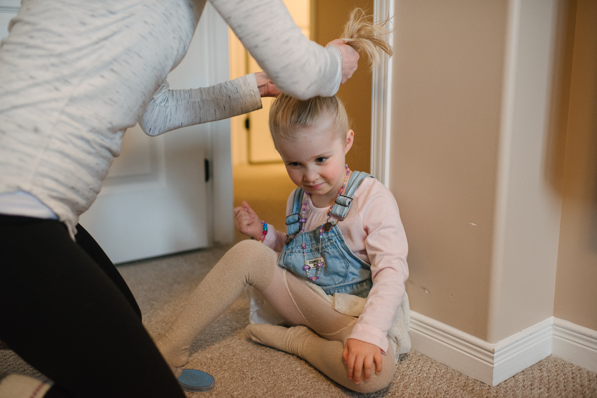 Mother styling daughter's hair in hallway