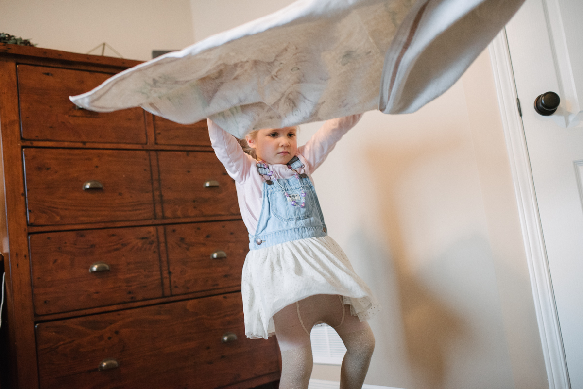 Girl playing with a blanket standing up