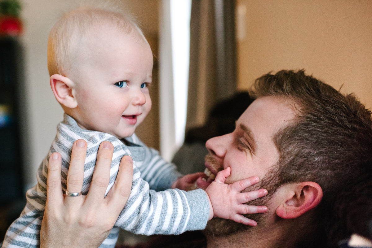 smiling baby holds father's face closeup in the living room