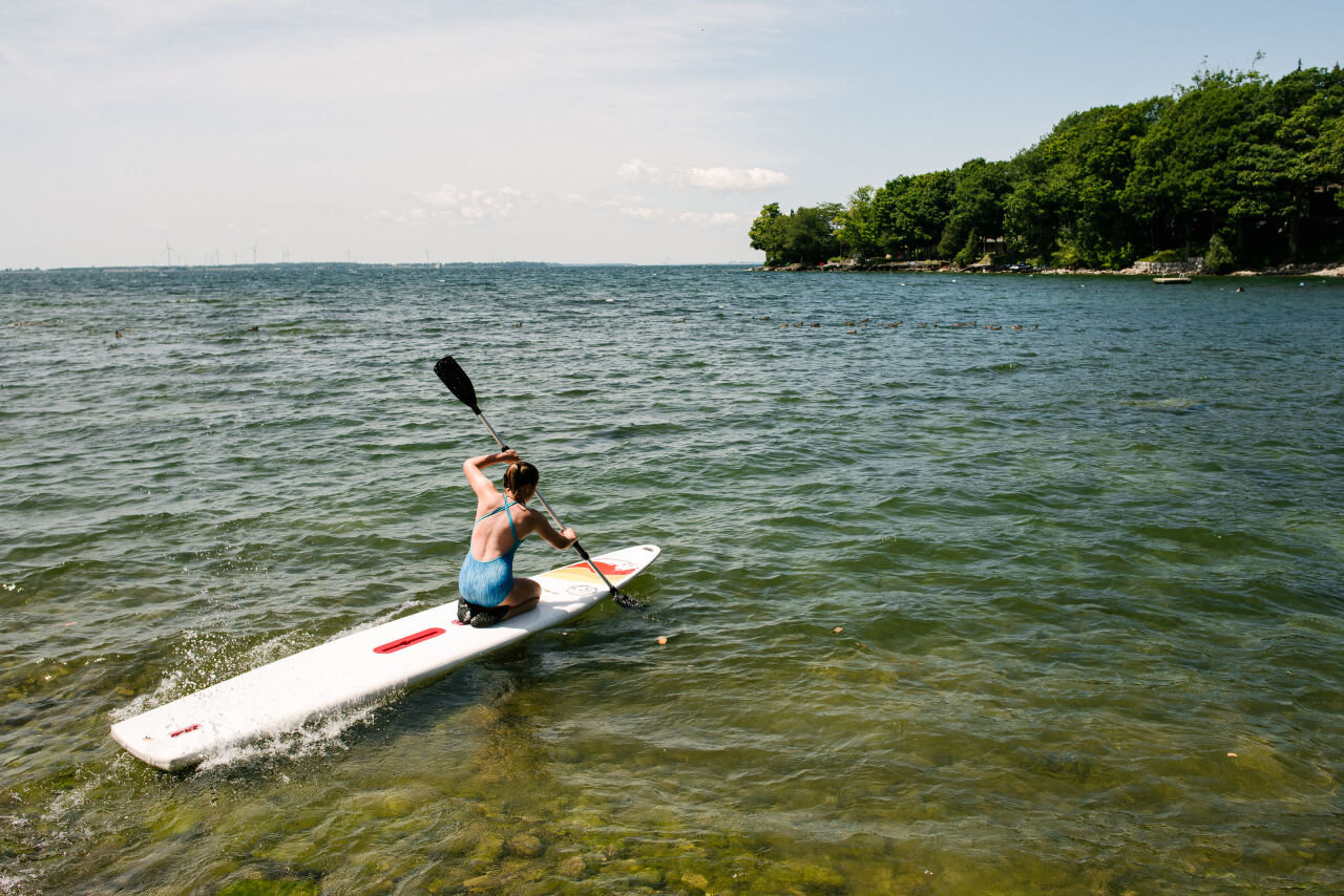 Young girl stand up paddle boarding on Lake Ontario during a family photography session