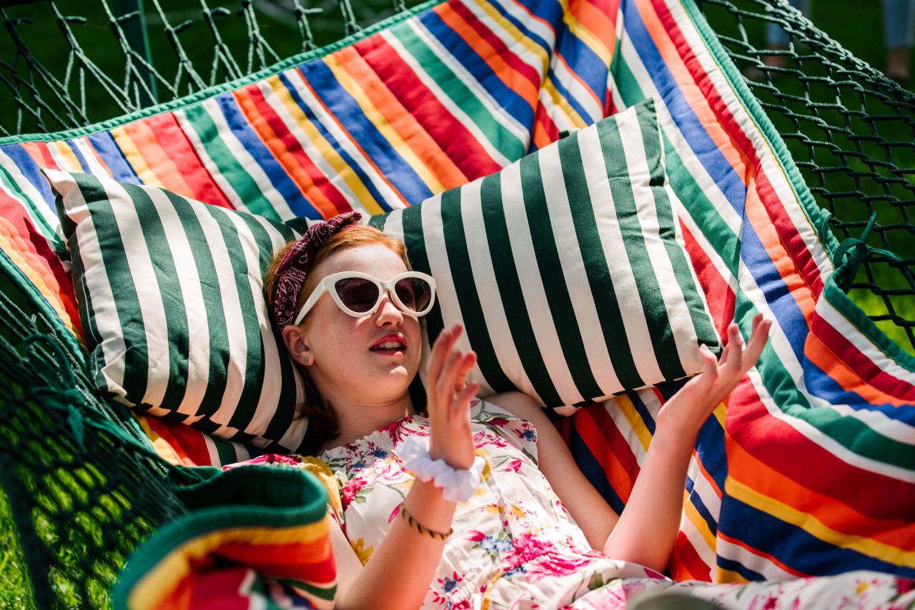 Young girl hanging out in hammock while wearing sunglasses in the summer during a family photography session