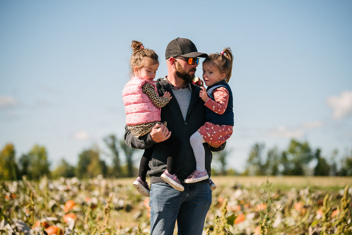 walking through the pumpkin patch near kingsotn ontario during a family photosession aimed at capturing candid moments in the year in the life family photography package