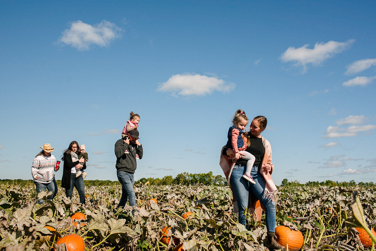family visits pumpkin patch during their candid family photography session in their year in the life photosession