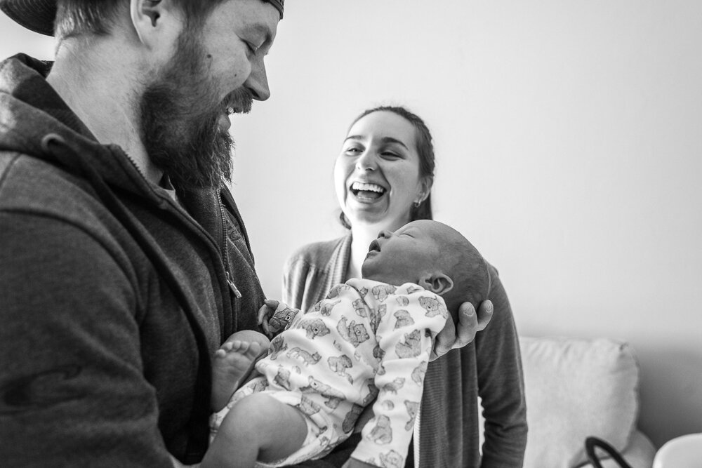 family laughing and enjoying their newborn baby