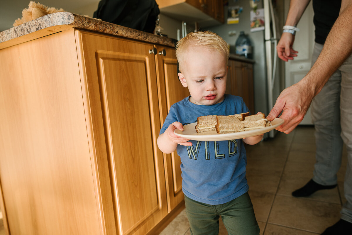 little boy holding a plate of sandwiches