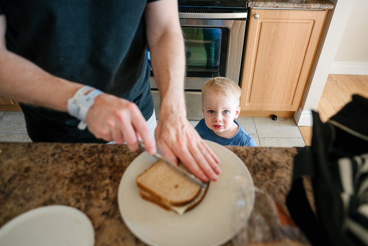 dad making lunch while little boy watches 