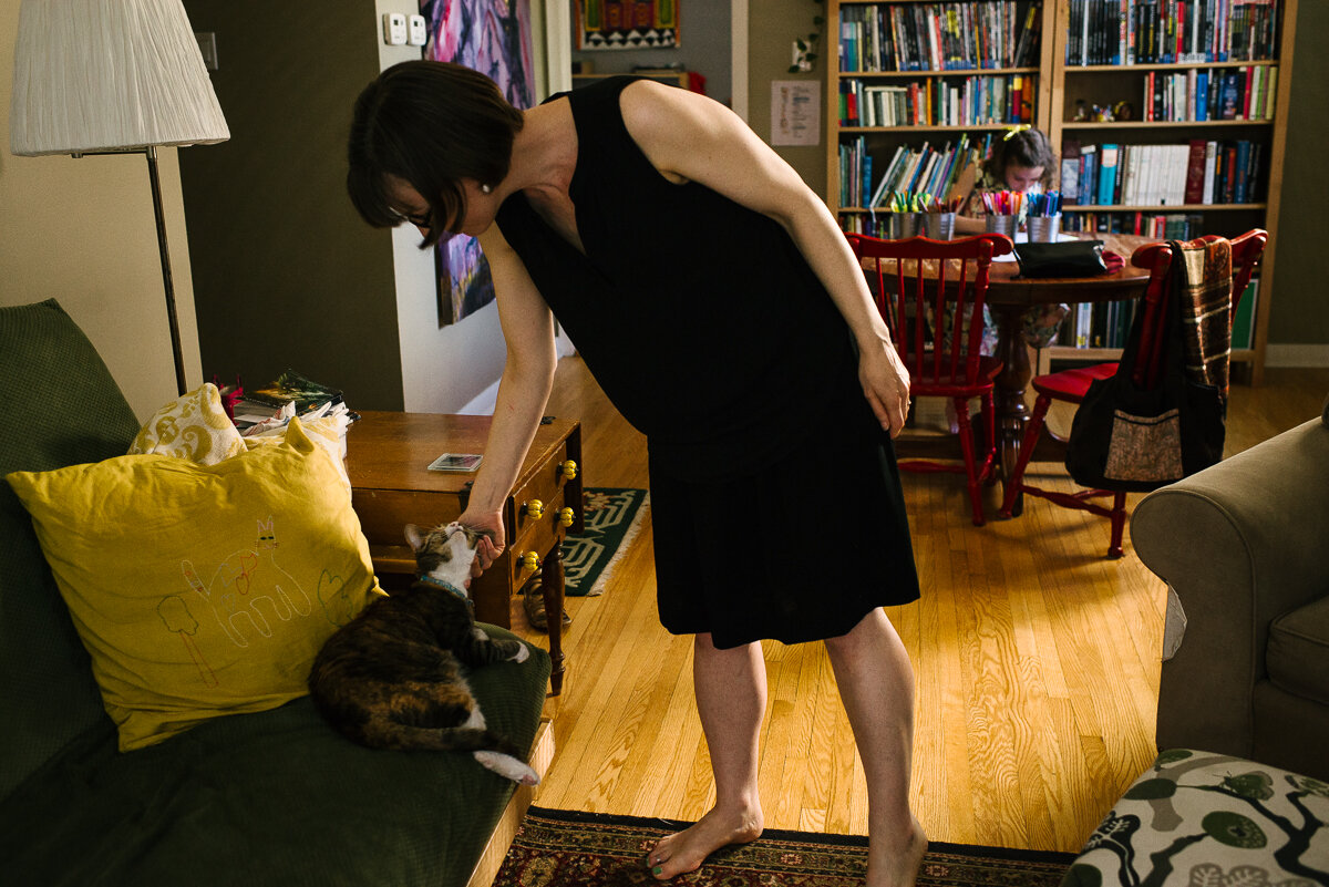 Woman petting family cat while on the couch during day in the life session 