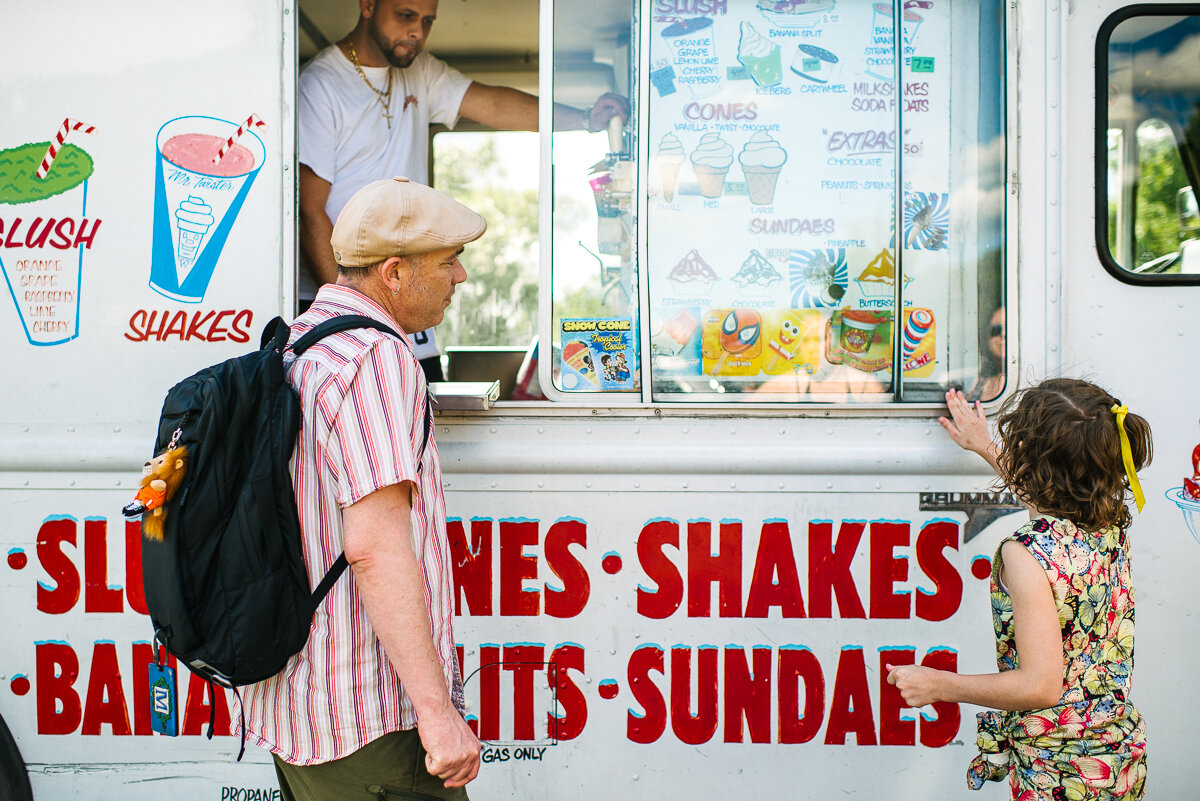 Father and daughter standing next to an ice cream truck 