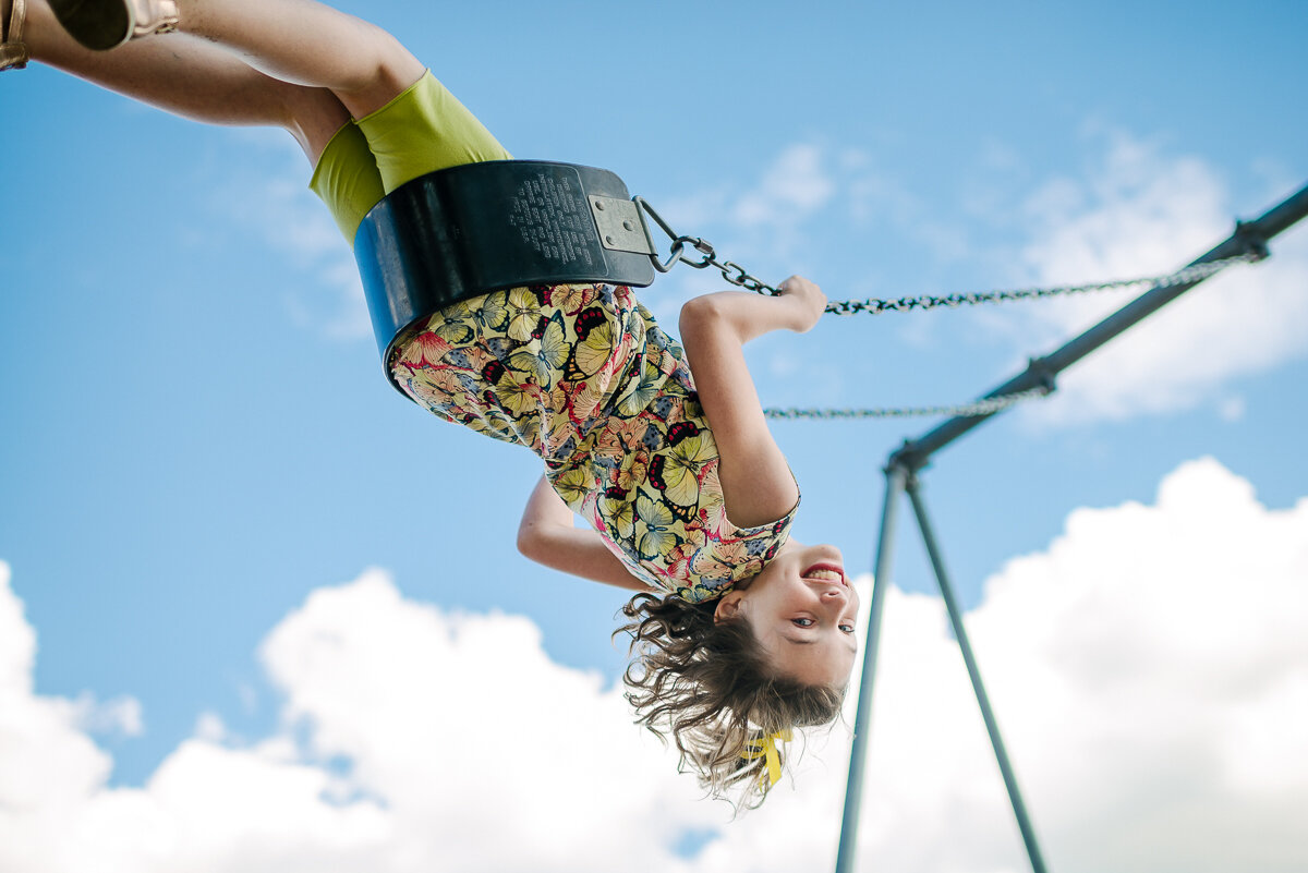 girl swinging very high, with only sky and clouds in the back ground 