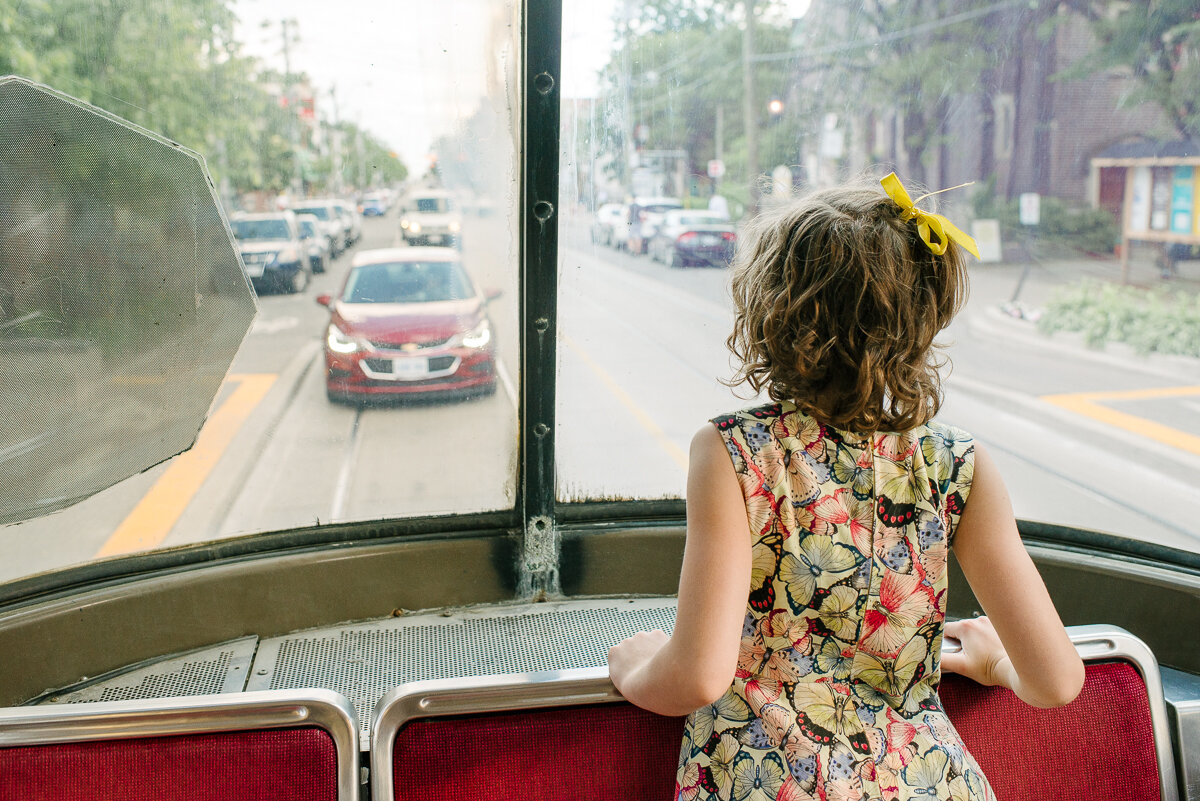 Little girl looking out the window of the street car 