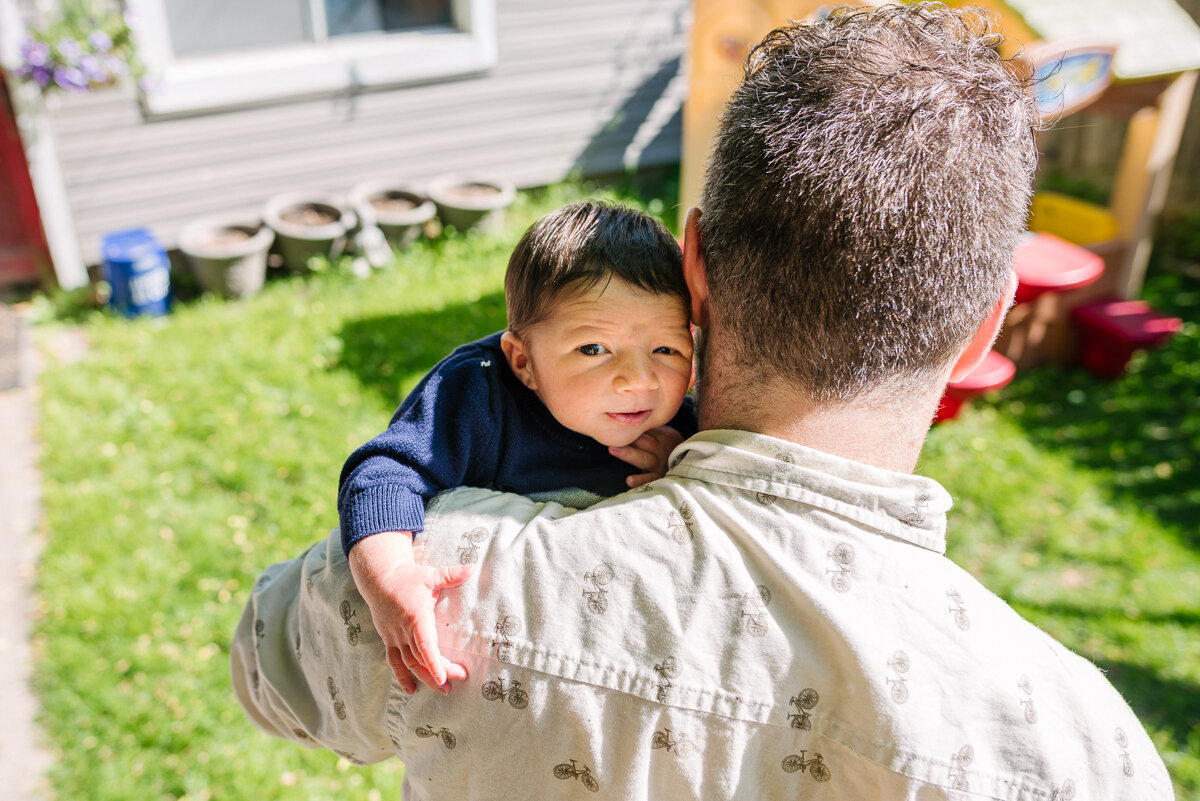 dad holding new baby boy in their backyard 