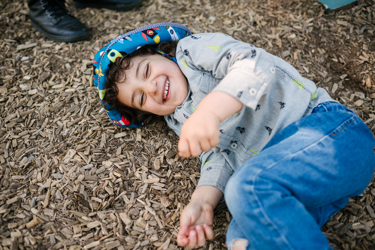 little boy rolling around on the ground laughing during family photo session