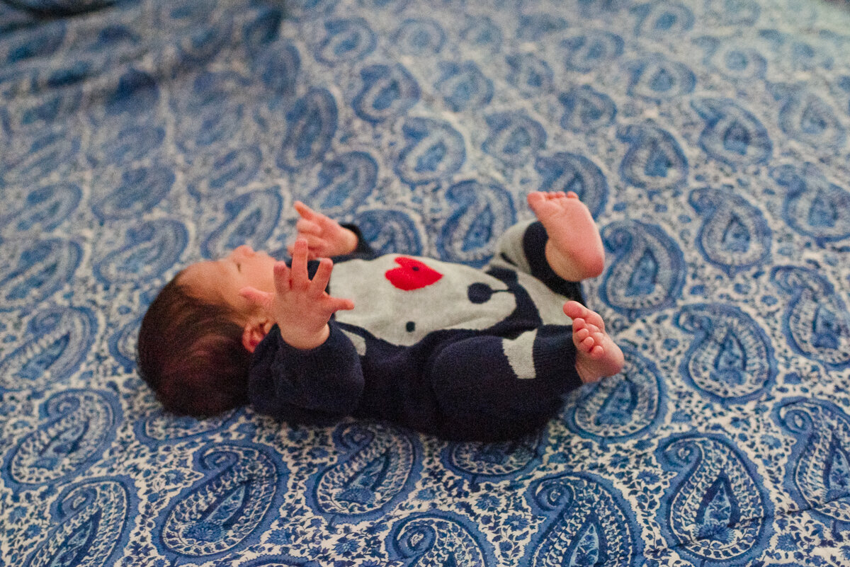 New born baby playing on bed