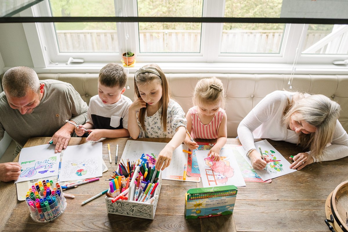 Mom, dad, son and daughters coloring together in painting books