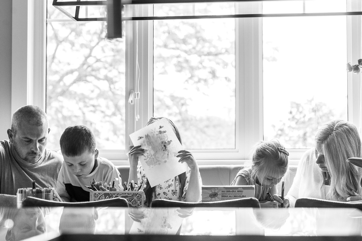 Black and white image of a happy family together enjoying drawing and coloring