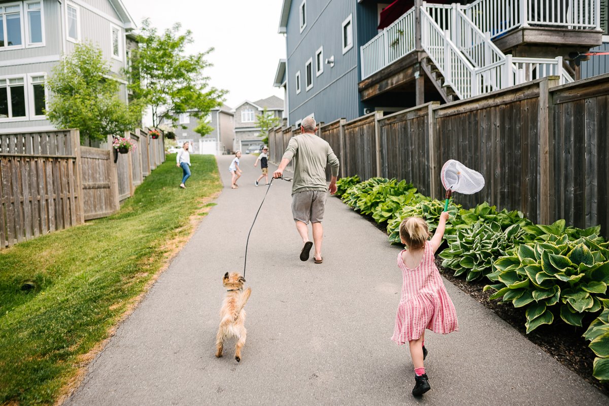 Dad running with her pup and daughter in the backyard.