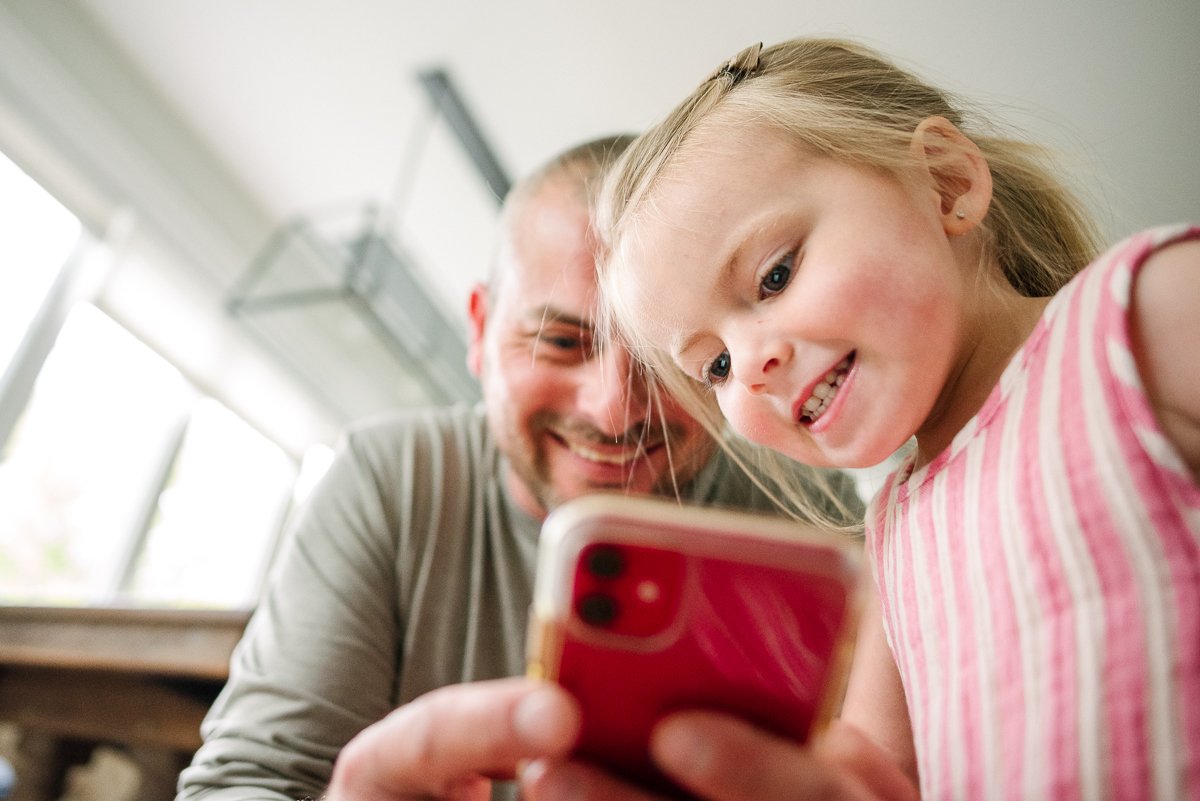 Father and daughter looking at the phone screen with smiles on their faces