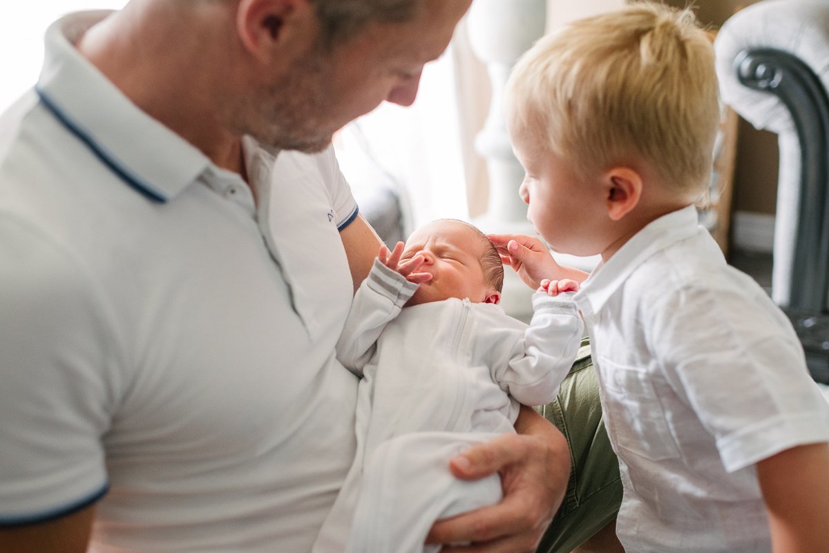 Newborn baby with his brother and father enjoying moment