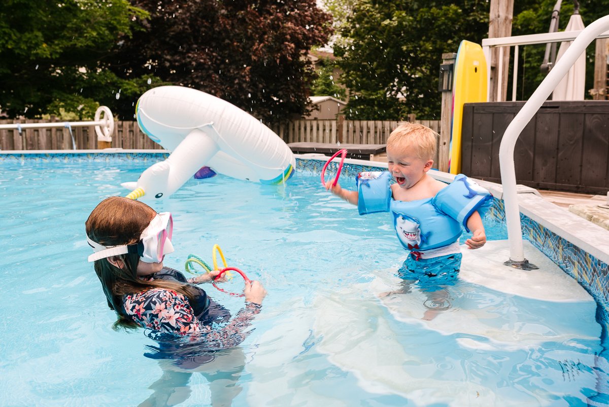 Little boy playing with his sister in the swimming pool