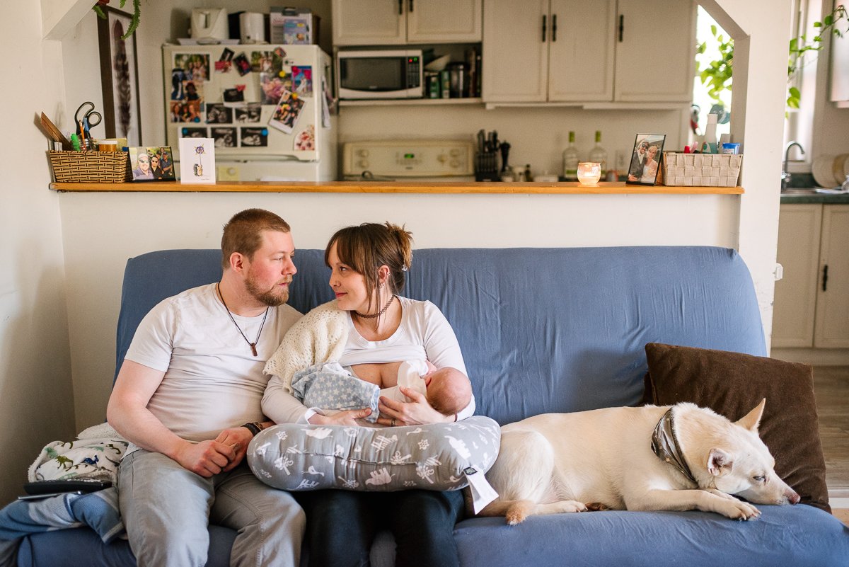 Mom and dad sitting on couch holding little baby