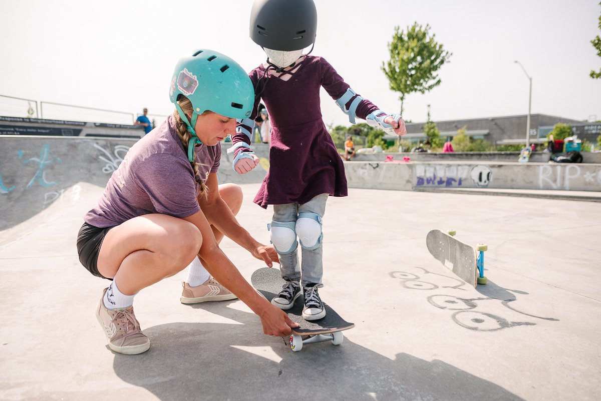 Two girls learning skateboard wearing blue and black helmet.