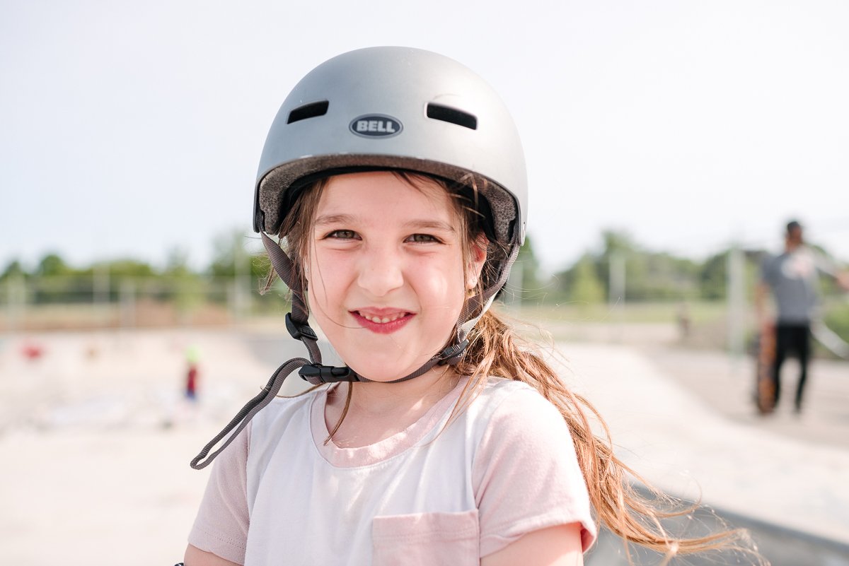 Cute happy girl wearing silver helmet, white and pink t shirt smiling.