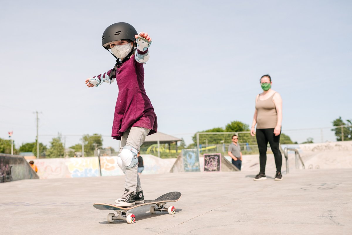 Girl in maroon top and black helmet skating in the playground