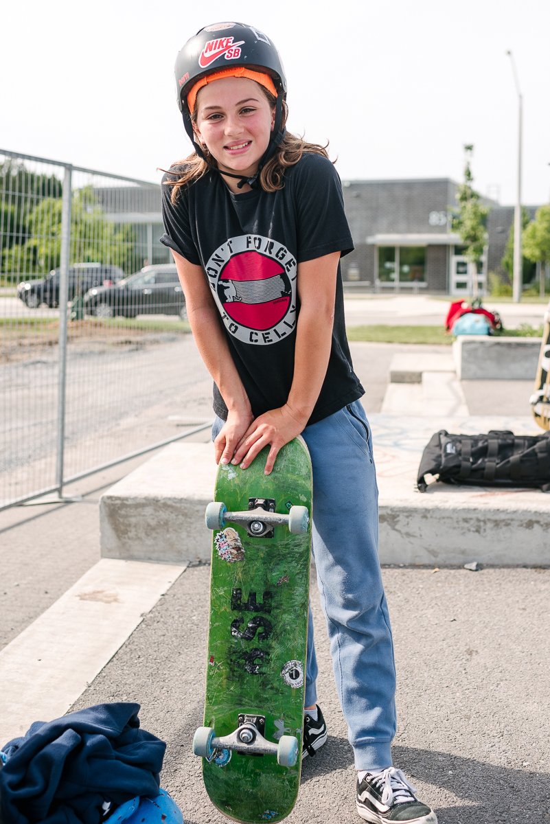 Girl wearing black top and helmet learning skateboarding.