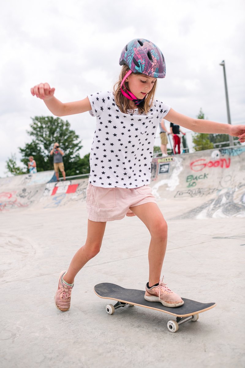 Girl wearing white and blue learning skateboarding 